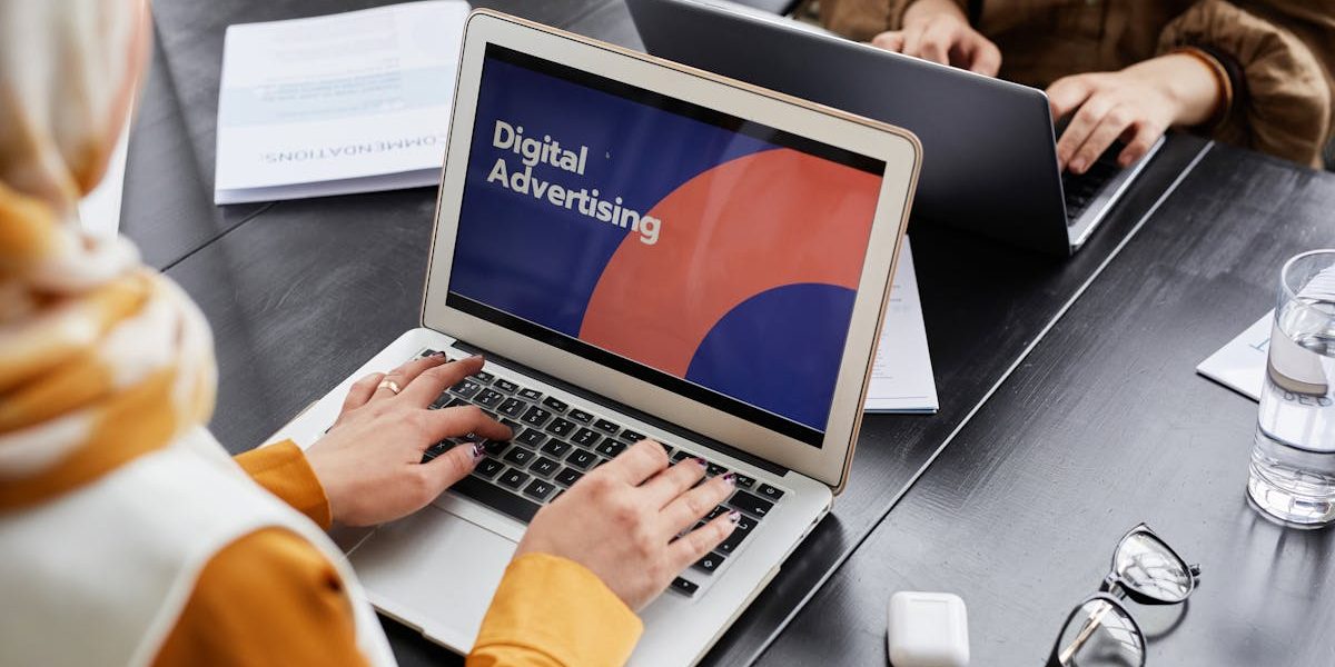 Two professionals work on laptops focusing on digital advertising in an office setting.